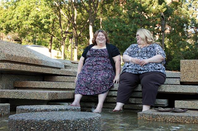 2 people laughing together while sitting outside.